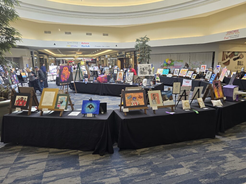 : Rows of student artwork displayed on easels and black-draped tables inside the Ohio Valley Mall during the Belmont County Celebration of the Arts.