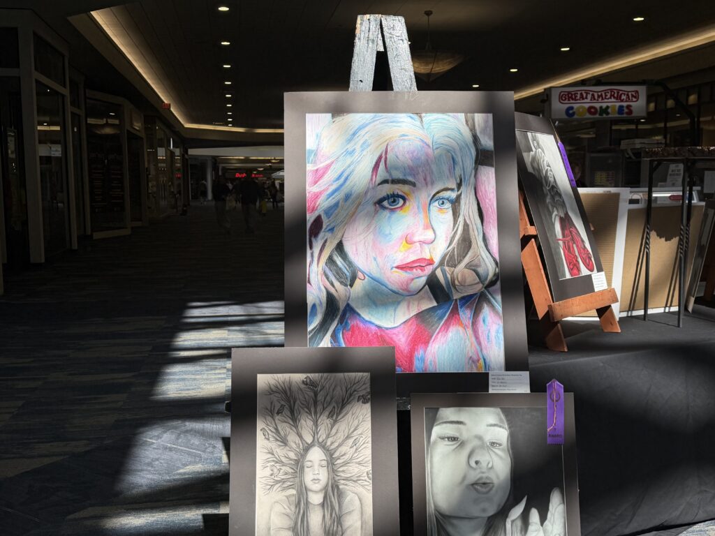 Rows of student artwork displayed on easels and black-draped tables inside the Ohio Valley Mall during the Belmont County Celebration of the Arts.