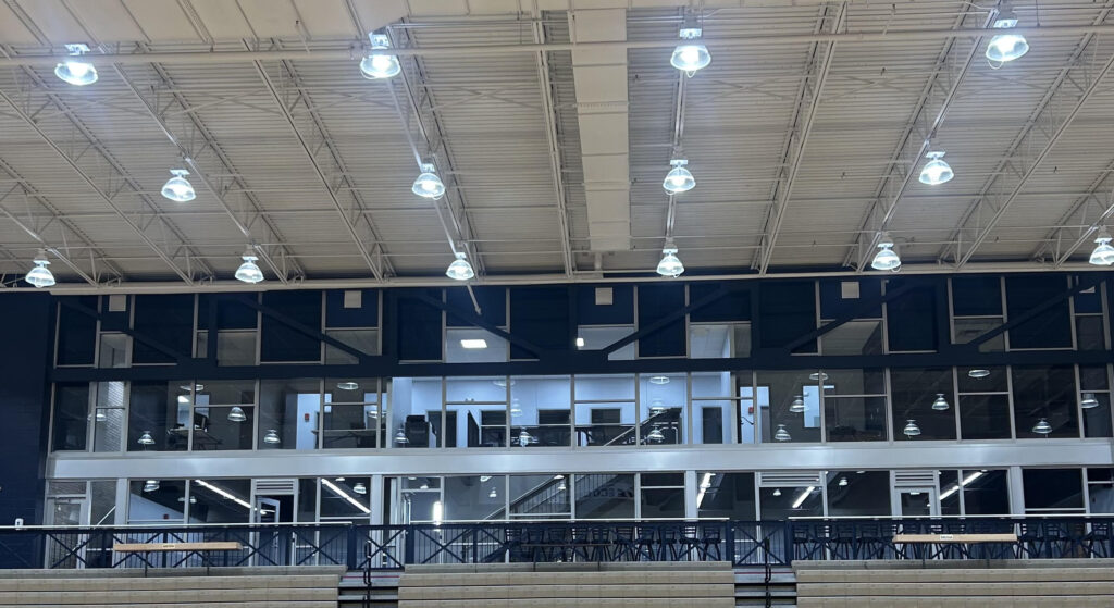 Interior view of The ECO Center's high-ceiling main floor with industrial pendant lighting, brick facade, and mezzanine level housing OHHC dental offices and event seating.
